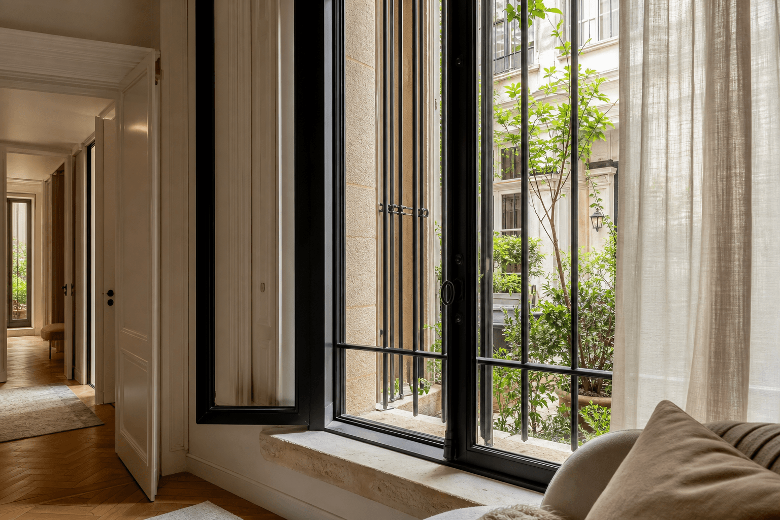 Fenêtre sécurisée d’un appartement parisien en rez-de-chaussée ouverte sur une cour plantée
